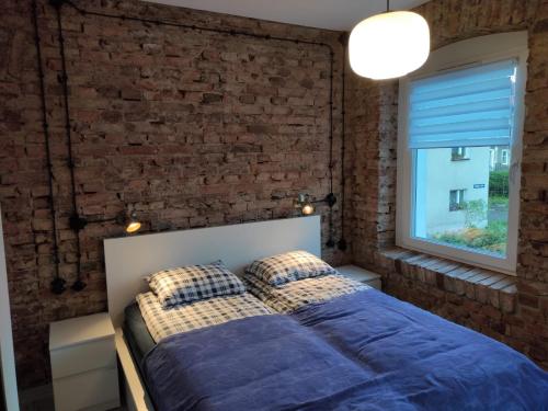 a bedroom with a brick wall and a bed with pillows at Apartament Loftowy Głuszyca in Głuszyca
