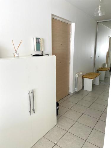 une cuisine blanche avec un réfrigérateur et une chambre dans l'établissement Appartement Résidence Quartier Vilette Paul Bert BOX GARAGE, à Lyon