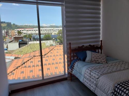 a bedroom with a bed and a large window at Hermoso departamento, céntrico y tranquilo in Quito