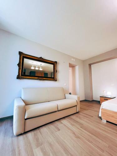 um sofá branco num quarto com uma cama e um espelho em Locus Amoenus Apartment a pochi passi dagli Scavi em Pompeia