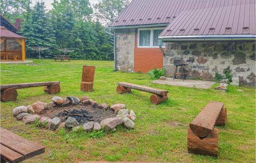 a fire pit with logs and benches in a yard at Cozy Apartment In Dominikowo With Wifi in Dominikowo