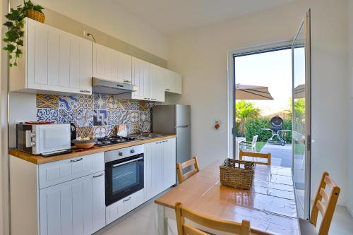 a kitchen with white cabinets and a table with a microwave at I giardini dell'Olimpo in Paestum