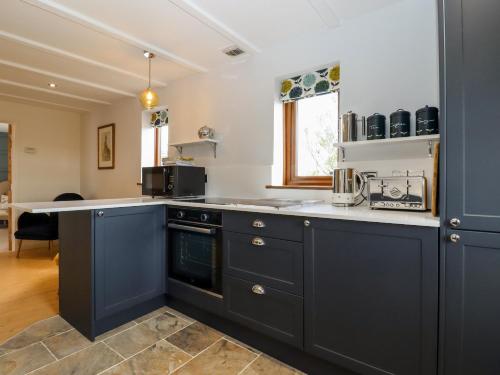 uma cozinha com armários azuis e uma bancada em Baa Lamb Cottage em Burmarsh