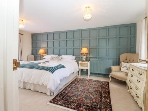 a bedroom with a large bed and a chair at Baa Lamb Cottage in Burmarsh