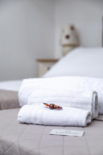 a white towel with a flower on it on a bed at Residenza Kastrum in Cagliari
