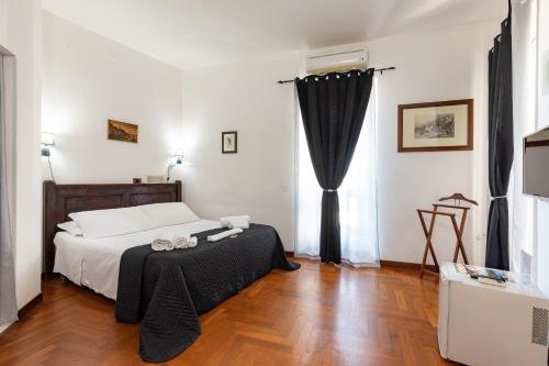 una camera da letto con un letto con tende nere e un pavimento in legno di Residenza Kastrum a Cagliari