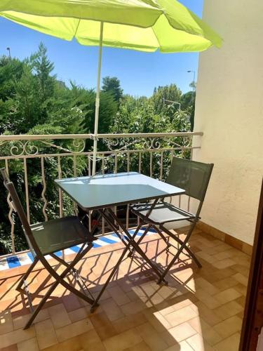 a table and two chairs with an umbrella on a balcony at La Garde : joli studio dans résidence in La Garde