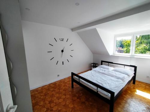 1 dormitorio con 1 cama y reloj en la pared en Dwupoziomowy apartament w dzielnicy nadmorskiej BalticRoom1 en Świnoujście