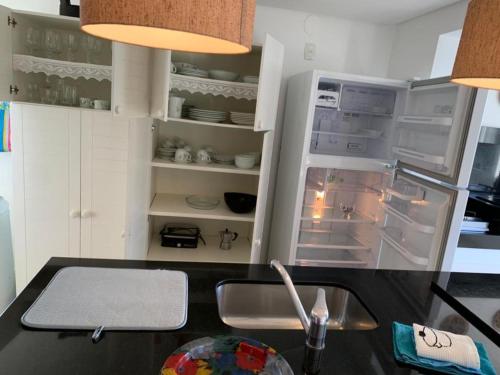a kitchen with a sink and an open refrigerator at Apartamento Manfroi in Bento Gonçalves
