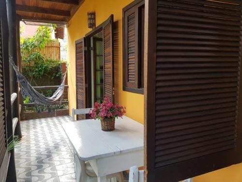 a porch with a table with a plant on it at Chalés e flats Recanto Primavera in Camburi