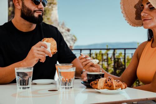 a man and woman sitting at a table eating food at Residenza Kastrum in Cagliari