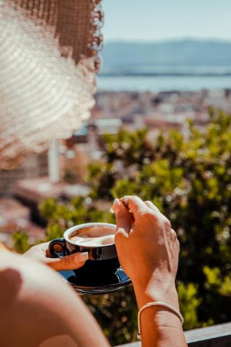 a woman holding a cup of coffee on a balcony at Residenza Kastrum in Cagliari