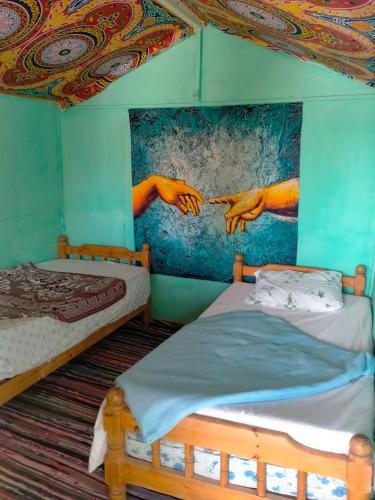 two beds in a room with a painting on the wall at Elbadawy camp in Nuweiba