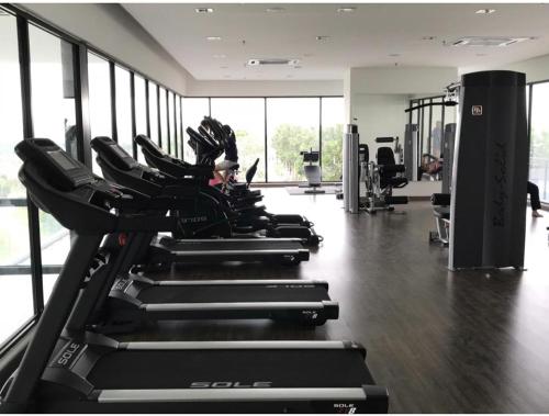 a row of treadmills in a gym with a woman in the background at Kyra Homestay Centrus SOHO Cyberjaya *wifi and pool* in Cyberjaya