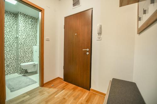 ein Badezimmer mit einem WC und einer Holztür in der Unterkunft Apartment Bono Lux City Kvart in Podgorica