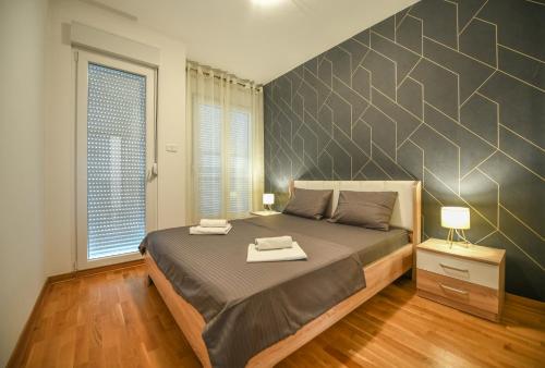 ein Schlafzimmer mit einem großen Bett und einer großen Wand in der Unterkunft Apartment Bono Lux City Kvart in Podgorica