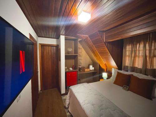 a bedroom with a large bed and a wooden ceiling at Casa Três Rios - Campos do Jordão in Campos do Jordão
