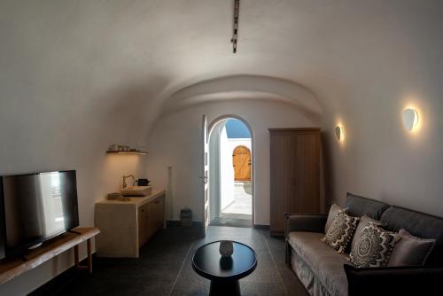 a living room with a couch and a tv at Lotus Cave Villa in Fira