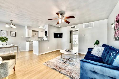 a living room with a blue couch and a ceiling fan at Global Cup City Outside & Tranquility Inside in Dallas