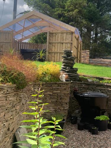 a garden with a stone wall and a building at Crockgarve B and B in Galbally