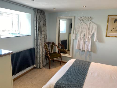 ein Schlafzimmer mit einem Bett, einem Stuhl und einem Spiegel in der Unterkunft The Waterside Rooms in Annan