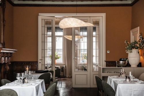 a restaurant with white tables and chairs and a chandelier at Villa Ostinato in Ostend