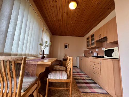 a kitchen with wooden cabinets and a table and chairs at Apartmán Penziónu Hrubjak in Oravská Polhora