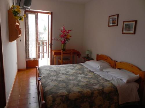 a bedroom with a bed and a table and a window at Rifugio Monte Baldo in Avio