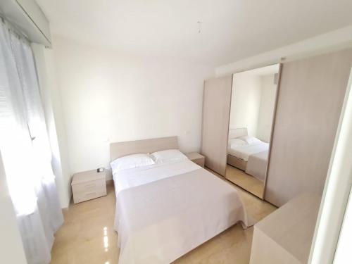 Un dormitorio blanco con una cama blanca y un espejo. en LE RIVE HOLIDAYS, en Desenzano del Garda