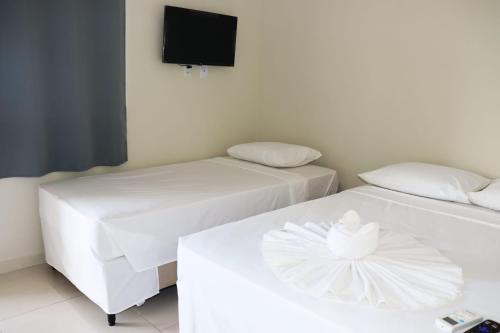 two white beds in a room with a tv at Pousada Sophia Beach in Salinópolis