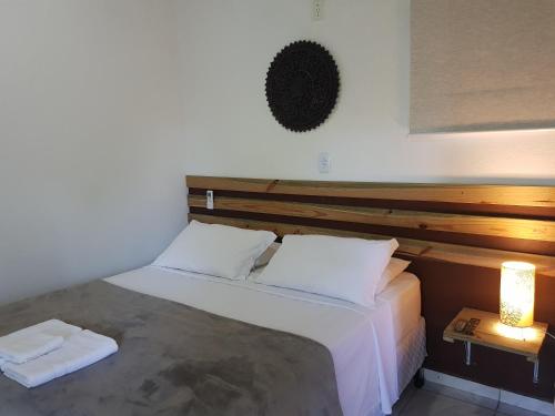 a bedroom with a large bed with a wooden headboard at Chalés e flats Recanto Primavera in Camburi