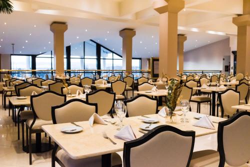 a dining room with tables and chairs and windows at Lagos Del Calafate in El Calafate
