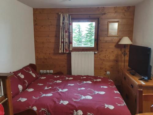 a bedroom with a red bed and a television at Premium Les Alpages de Chantel in Arc 1800