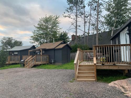 una terraza de madera con un banco y una casa en Glen Garry motel and cottages, en North Bay