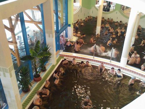 a crowd of people in a swimming pool in a building at Cserke-Thermál Apartman in Cserkeszőlő