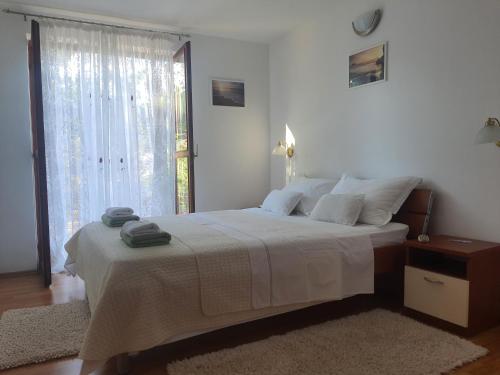 a white bedroom with a large bed with a window at Apartman Sutivan in Sutivan