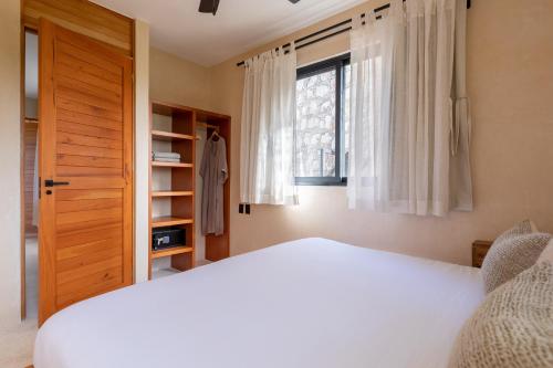 a bedroom with a white bed and a window at Cucu Hotel El Cuyo in El Cuyo