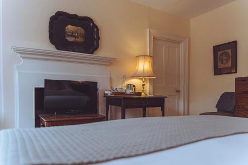 a bedroom with a fireplace and a bed and a television at Spread Eagle Inn in Stourton