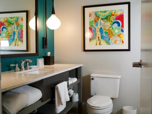 un bagno con un lavandino e un water con due quadri sul muro di Hotel Indigo Atlanta Vinings by IHG ad Atlanta