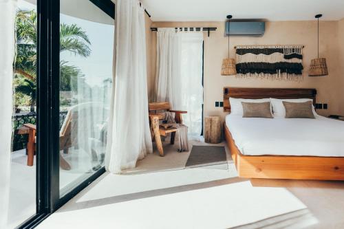 een slaapkamer met een bed en een groot raam bij Cucu Hotel El Cuyo in El Cuyo