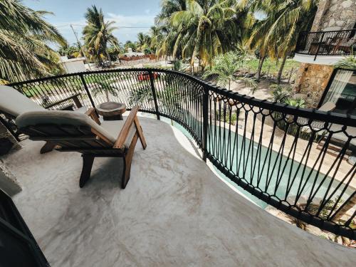 a balcony with a chair and a fence and palm trees at Cucu Hotel El Cuyo in El Cuyo