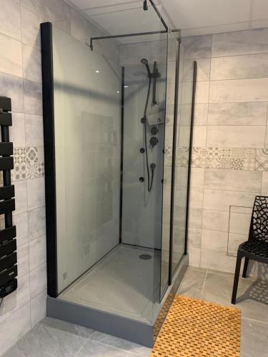 a glass shower stall in a bathroom with a chair at La Maison Clémenso in Cluny