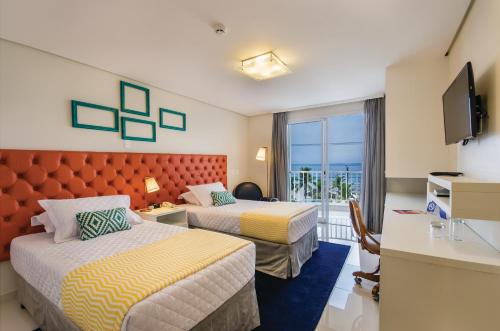 a hotel room with two beds and a television at Doral Guarujá in Guarujá