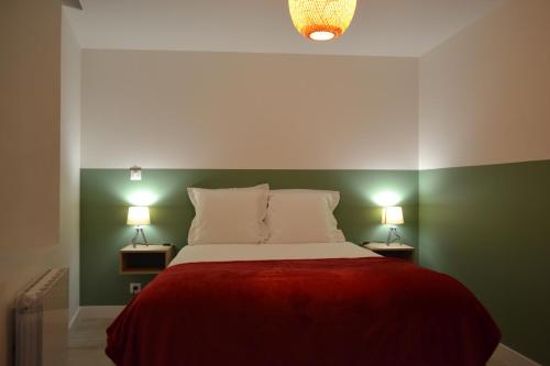 a bedroom with a bed with a red blanket and two lamps at L'essentiel de Chartres in Chartres