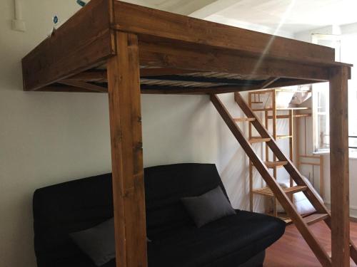 a wooden bunk bed with a black couch in a room at appartement Victor Hugo 2 D et sa pizza offerte in Aurillac
