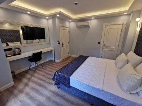 Dormitorio con cama, escritorio y TV en Luxx Garden Hotel en Estambul