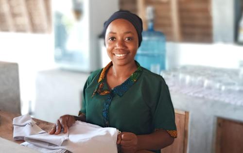 a woman sitting at a table smiles at the camera at Kijani Beach Villas in Bwejuu