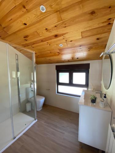 baño con aseo y lavabo y techo de madera. en Casa Los Rinocerontes, en Penagos