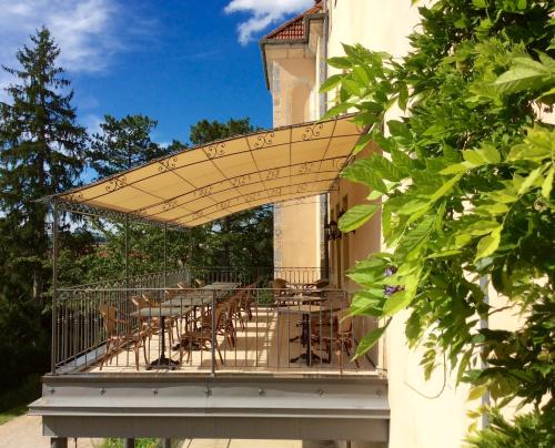 a patio with tables and chairs on a balcony at Hôtel Restaurant Spa Le Sauvage in Besançon