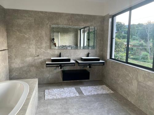 a bathroom with two sinks and a tub and a mirror at Ezulwini Executive Apartments in Lobamba